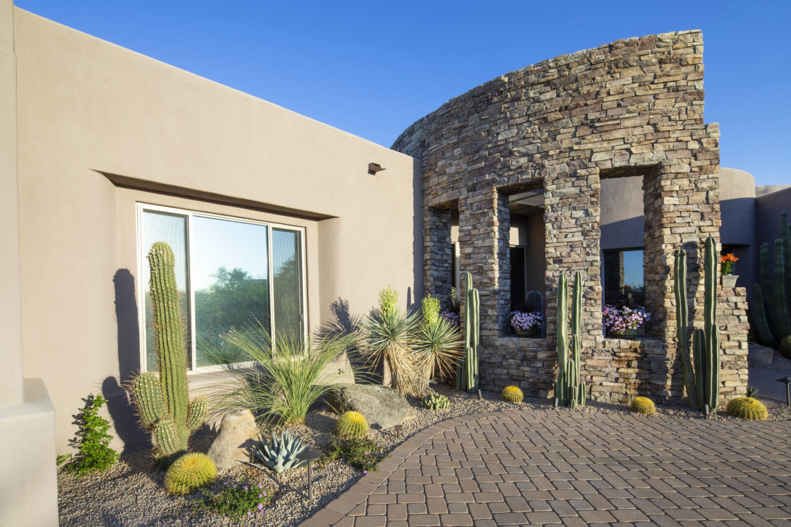 A stone building with cactus and plants in front of it.