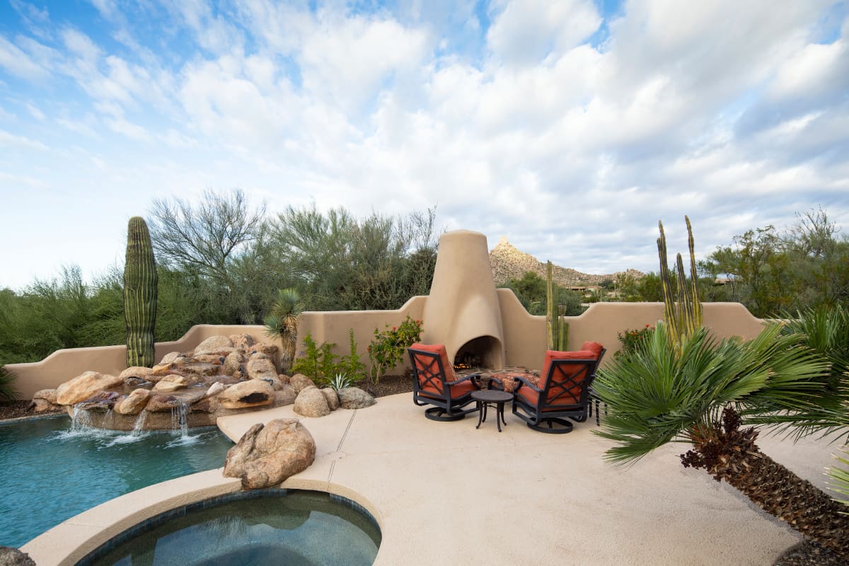 A couple of chairs and a fire place in the middle of a yard.