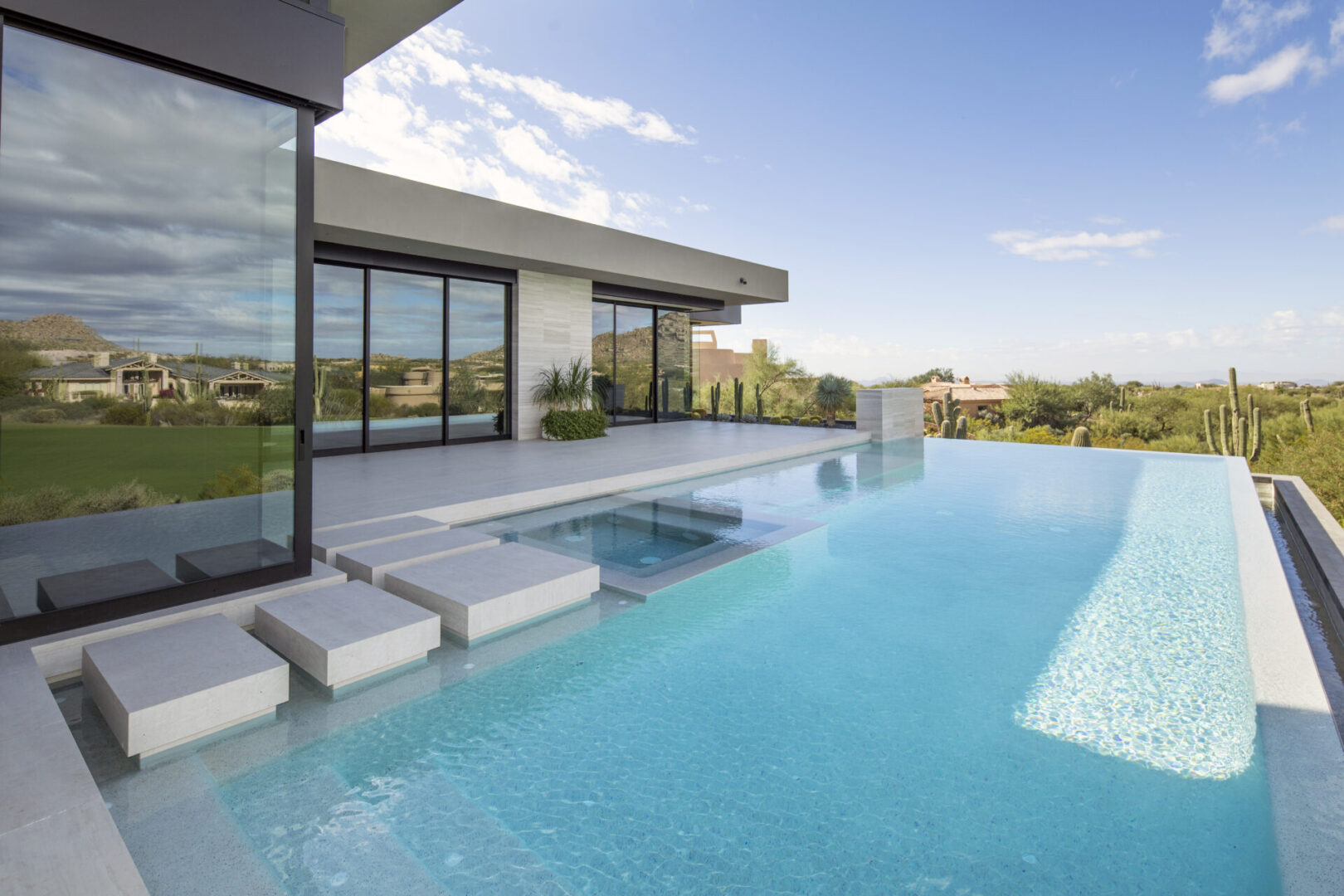 A pool with a large glass wall and a sky background