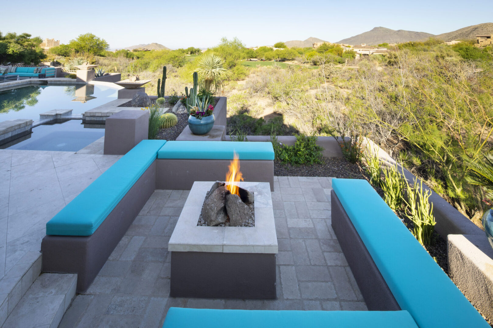 A fire pit with blue seats and pillows around it.