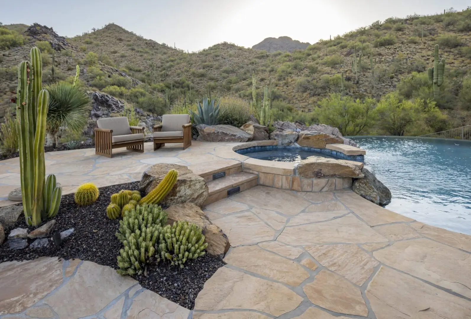 A pool with a bench and a stone patio.