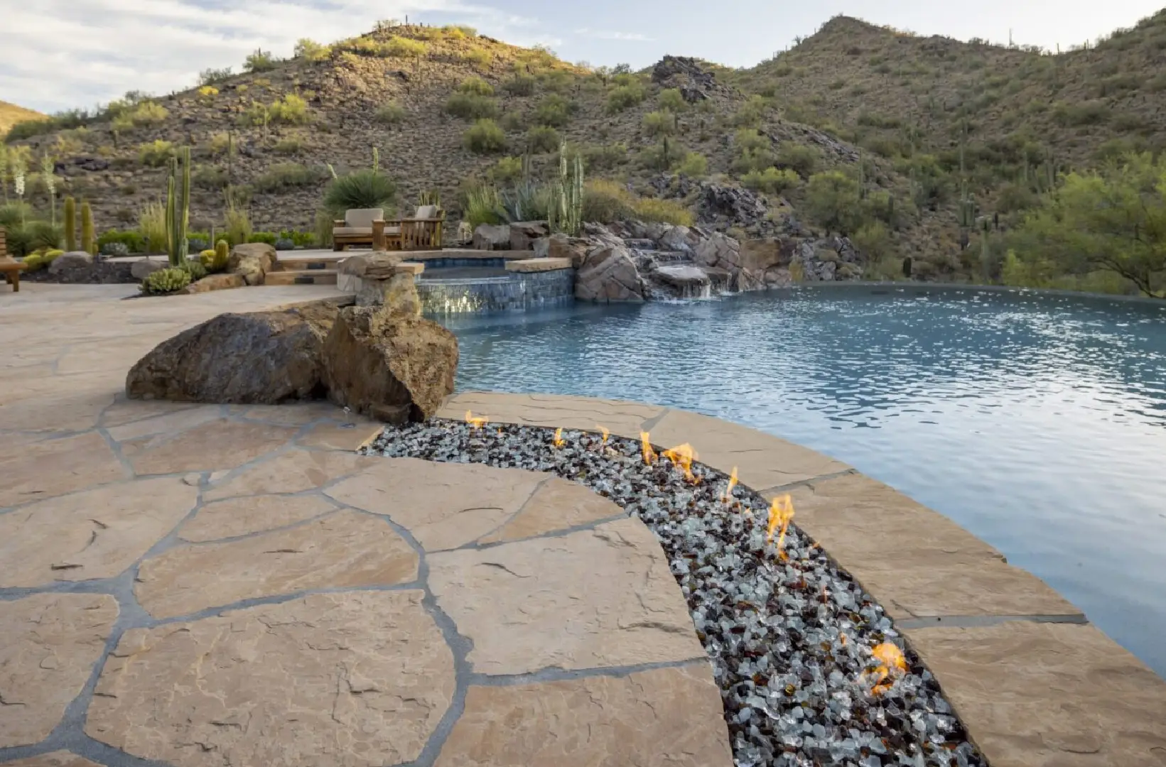 A pool with rocks and fire pit in the middle of it.