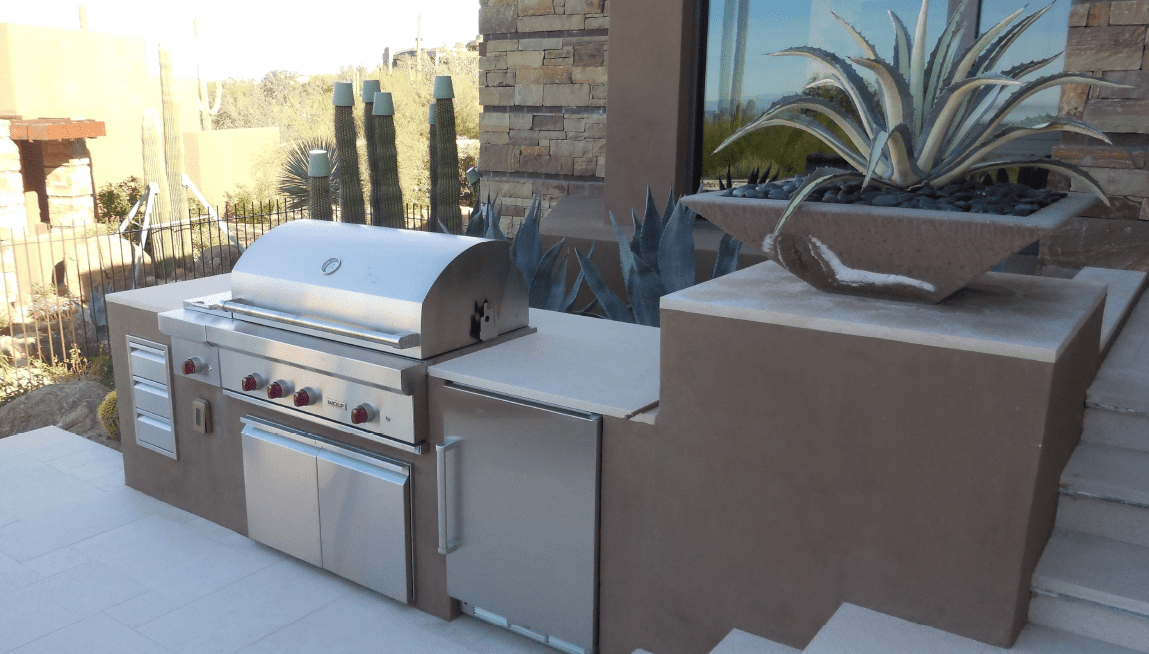 A bbq grill and refrigerator on the patio.