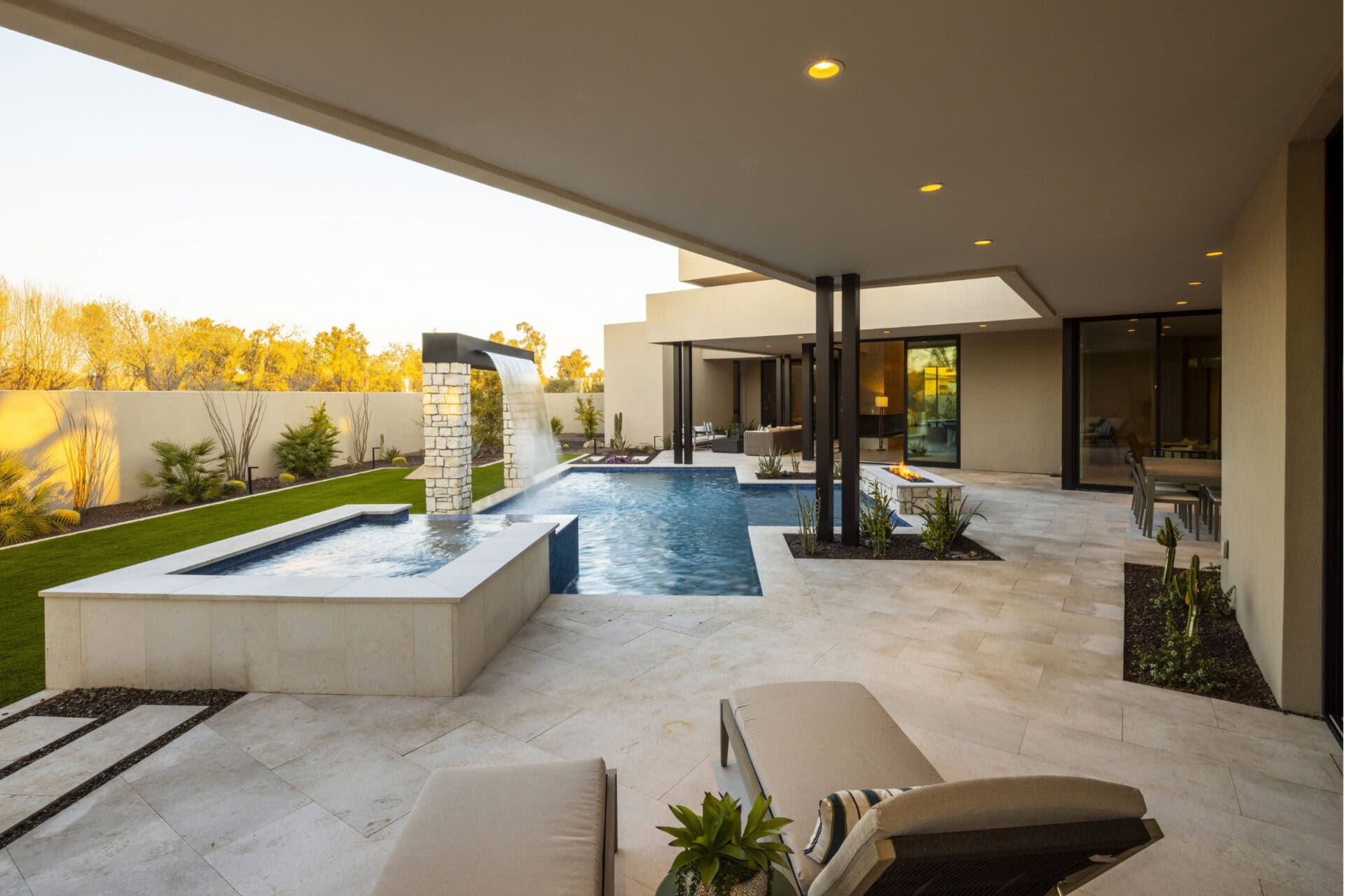 Luxury landscape design trends featuring a stone patio and custom pool.