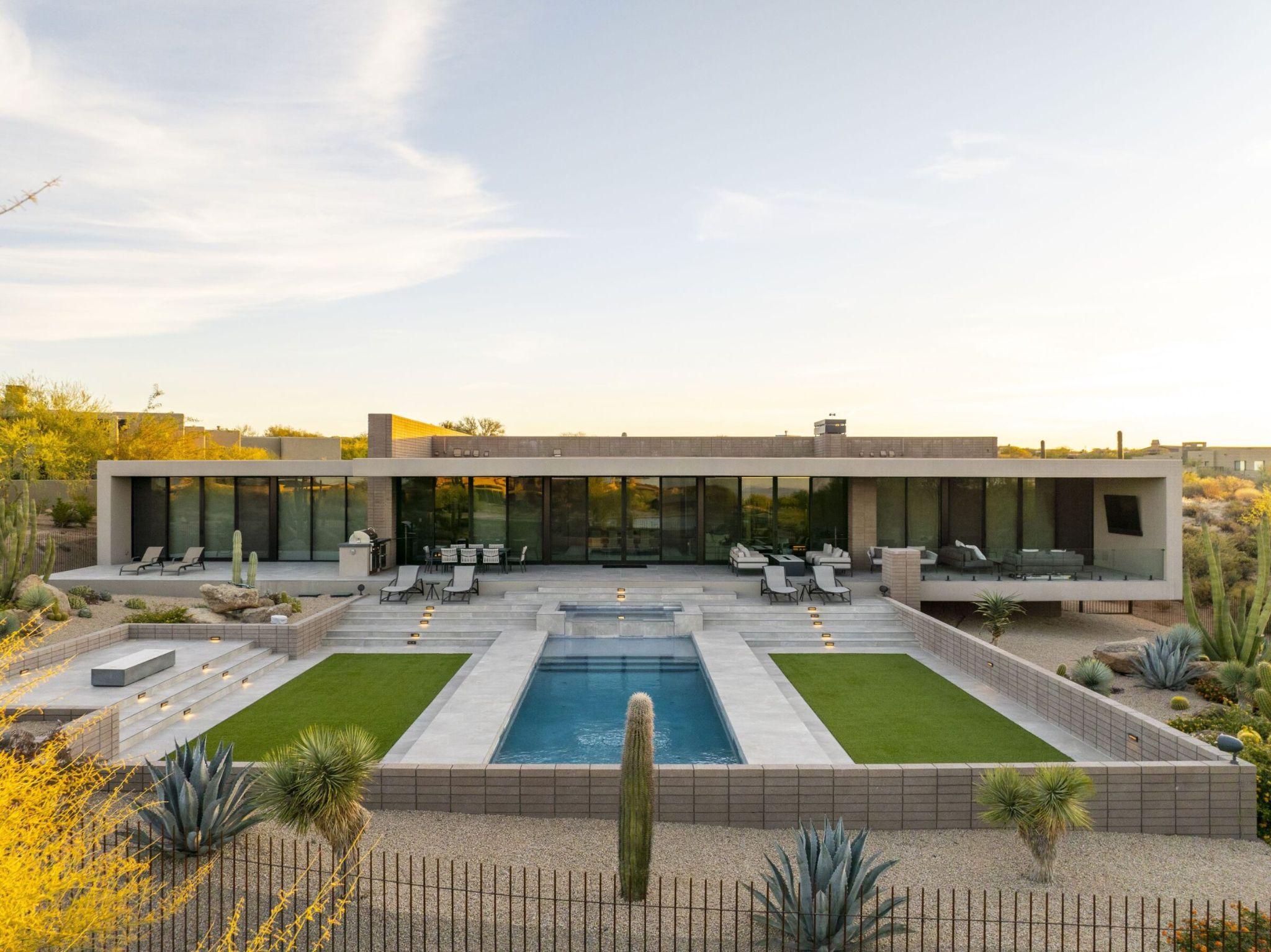 Modern desert home with tiered patio, geometric pool, and minimalist landscaping integrated into an Arizona hillside