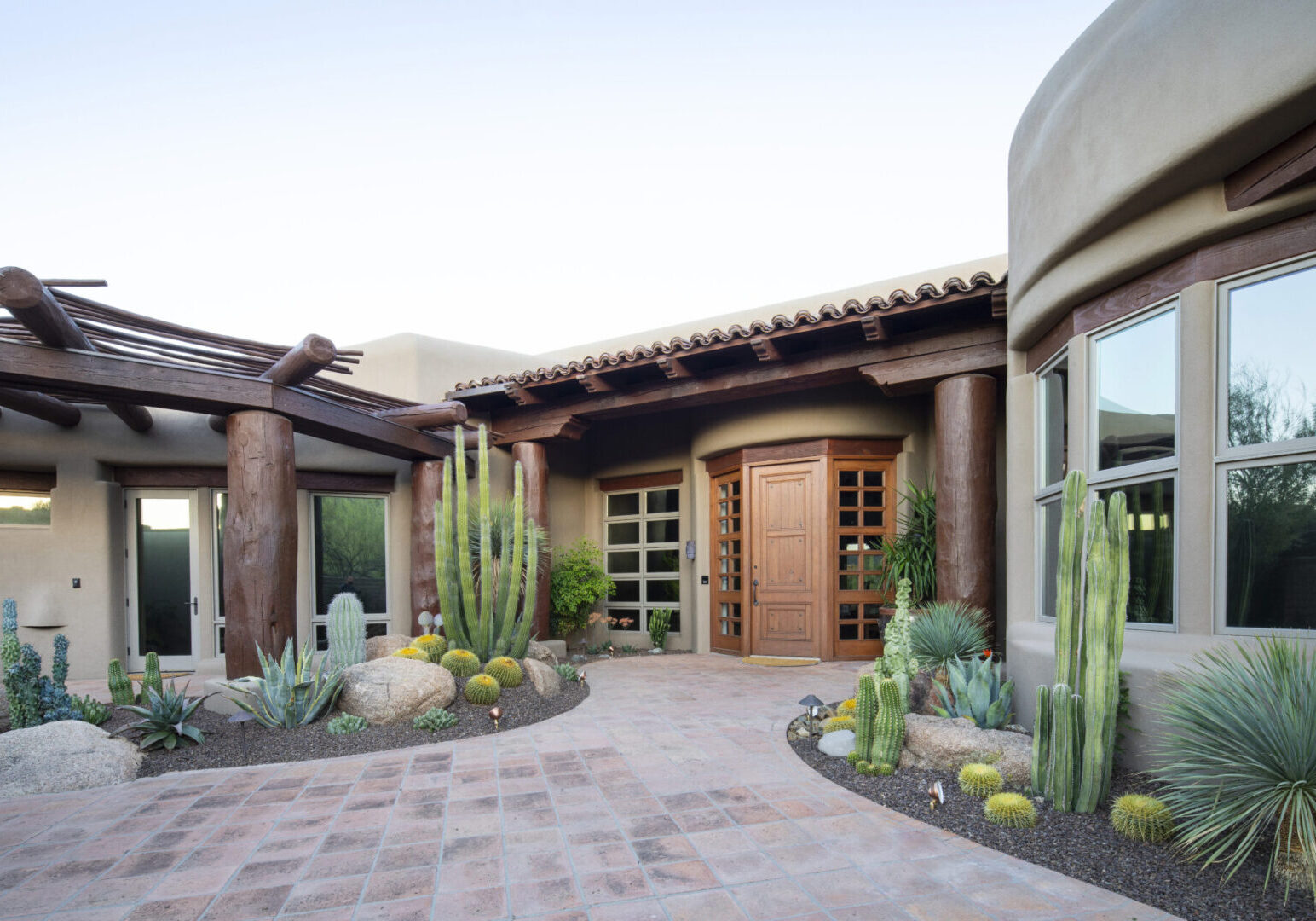 A large home with cactus and plants in the front yard.