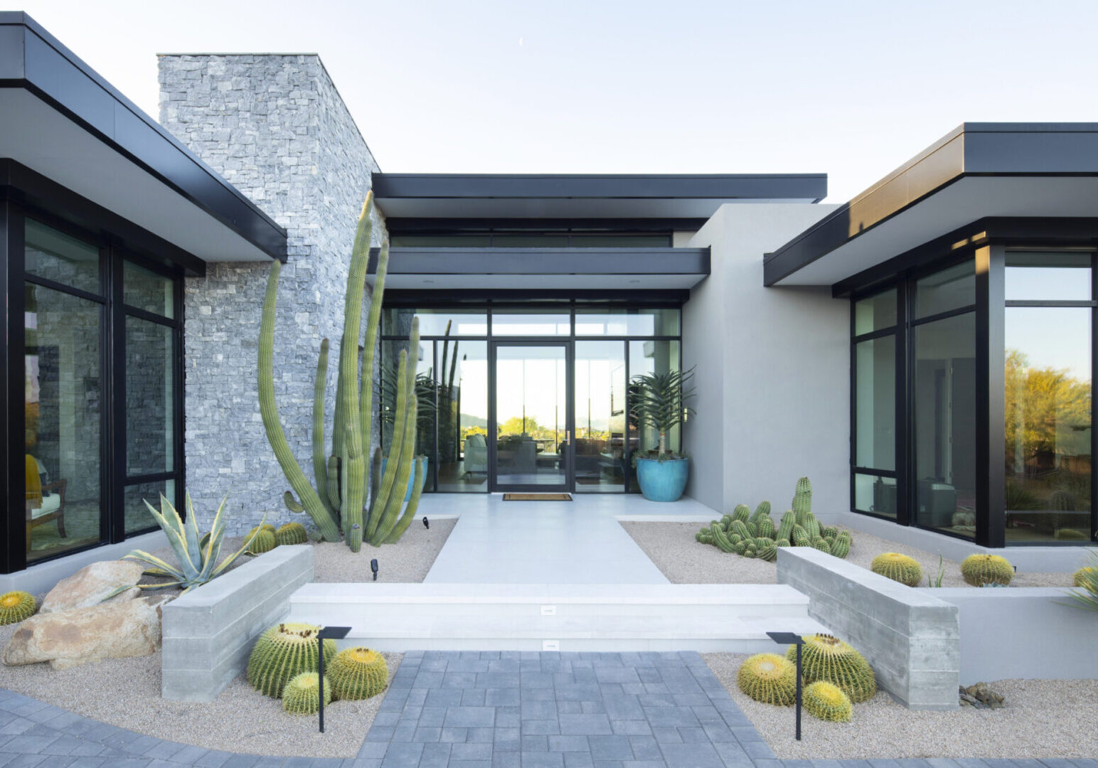 A large modern house with a cactus in the middle of it.