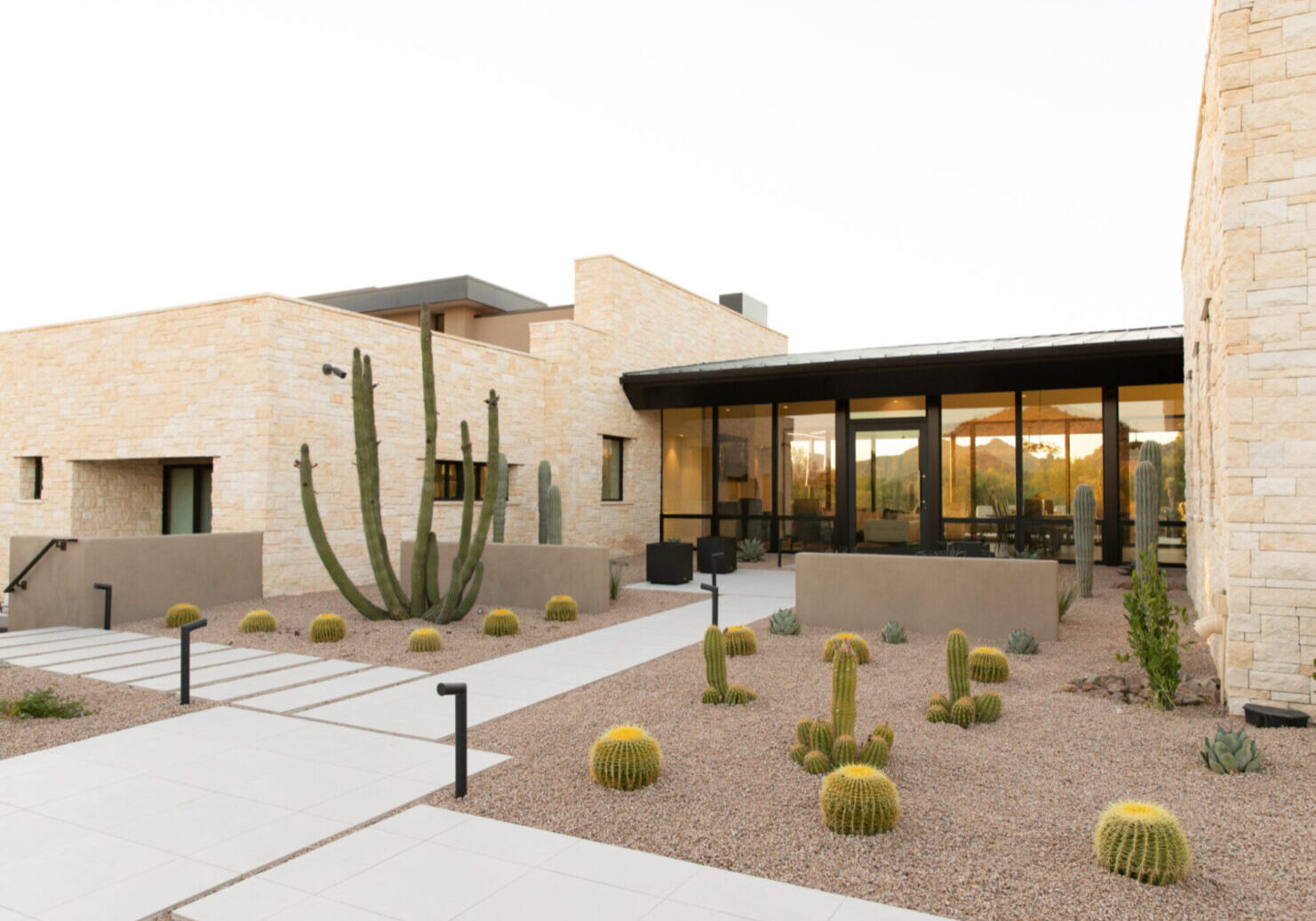 A building with many cacti in the front yard.